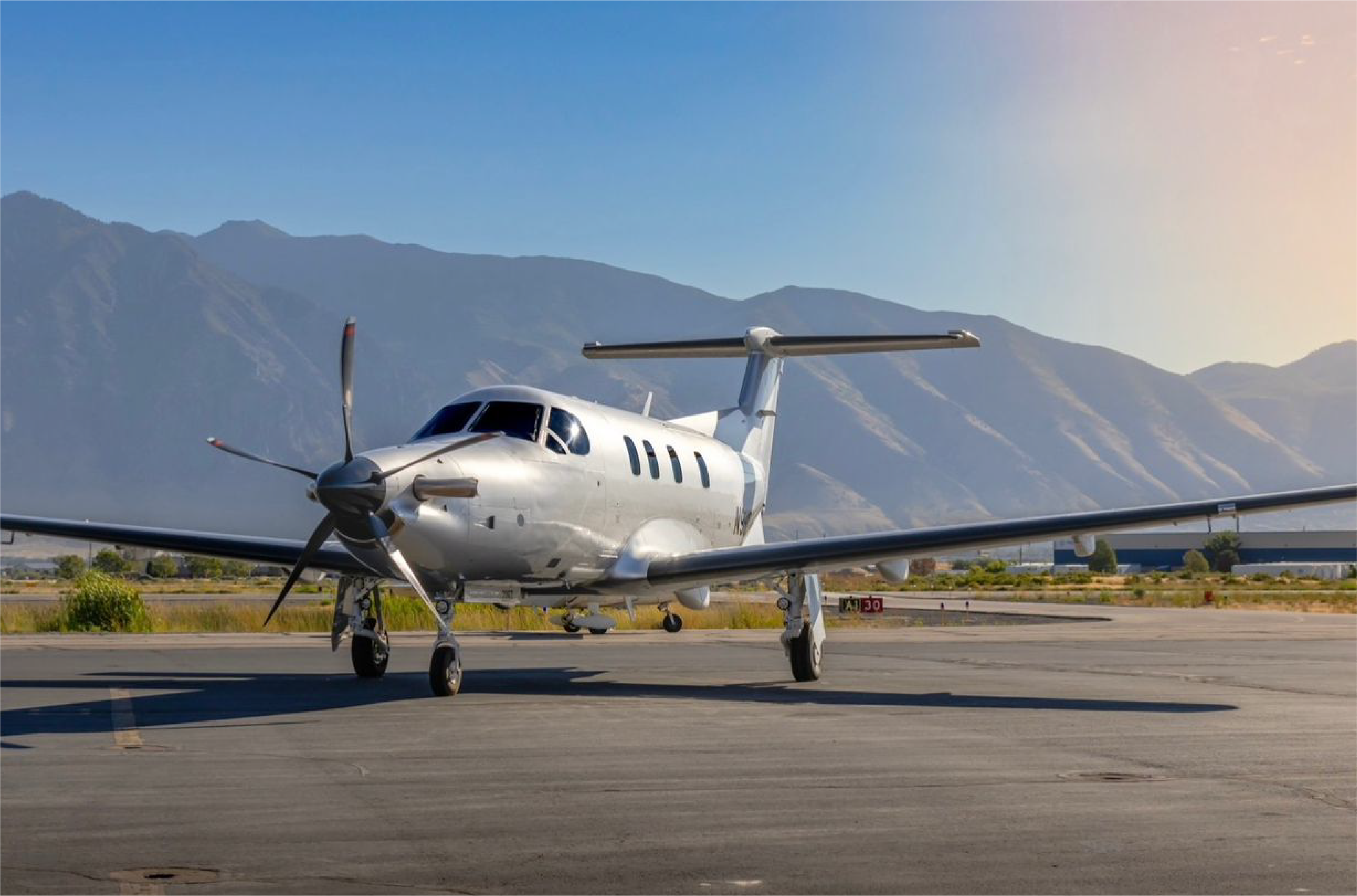Avión privado en pista con montañas de fondo